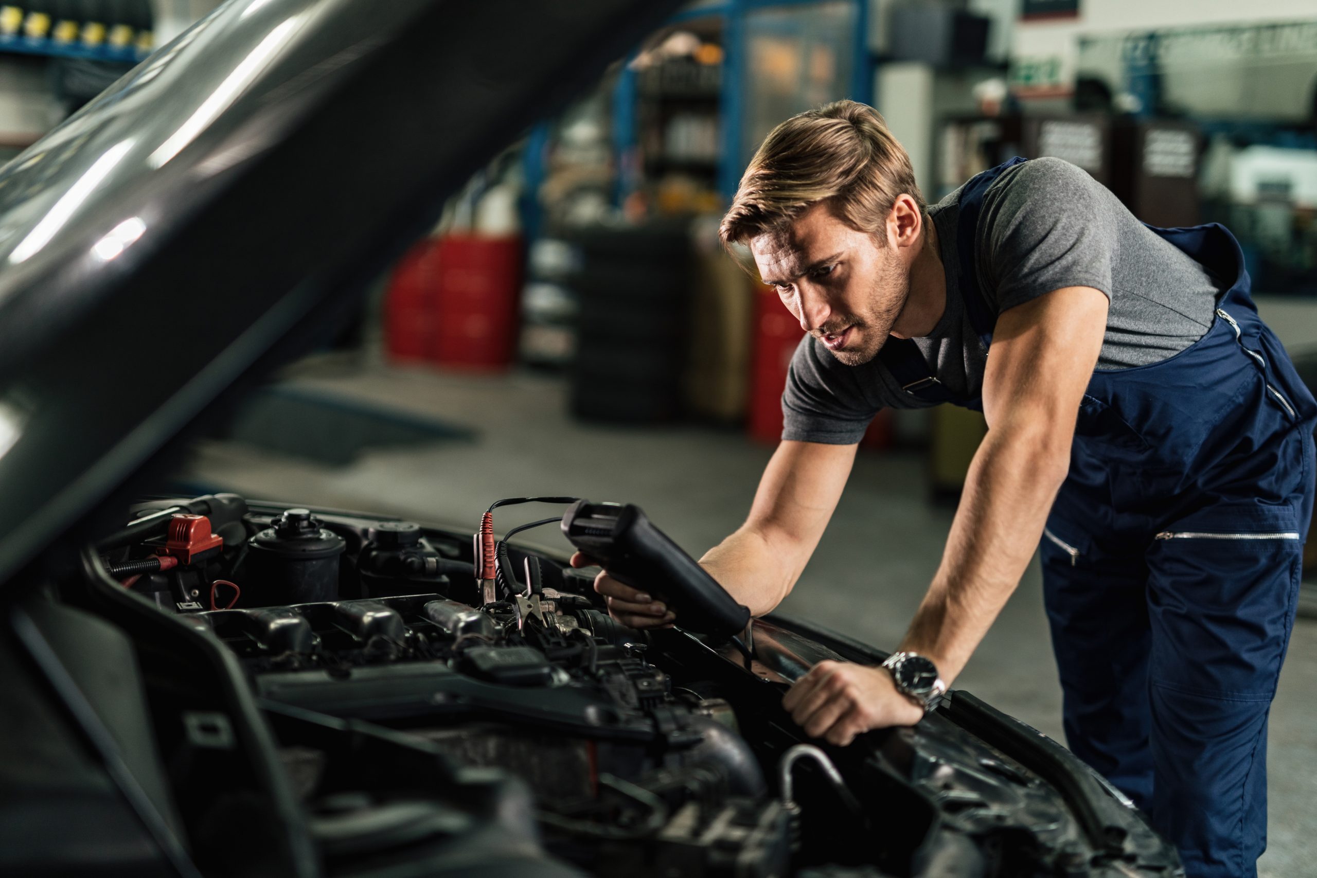 young mechanic with diagnostic tool analyzing car engine problem