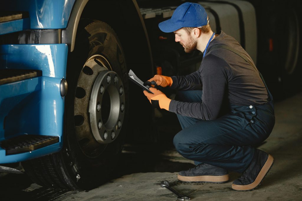 Mechanic checking ABS system and brake fluid reservoir under car bonnet.