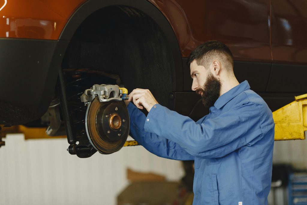 Close-up of new brake pads and shiny brake discs being fitted by a technician.